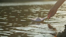 Woman Put Paper Ship Boat On Water In The Park Close Up. Origami Paper Crane On A Pond. Natural Lake View On Sunny Day