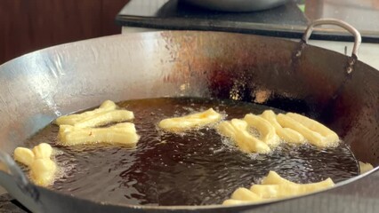 Sticker - 4K deep-fried dough stick or patongko being fried in a pan with boiling oil, Thailand street food breakfast favorite among tourists