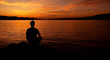 sylwetka mężczyzny medytującego na plaży przy zachodzie słońca