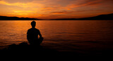 Fototapeta  - sylwetka mężczyzny medytującego na plaży przy zachodzie słońca