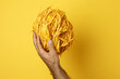 Close-up of a hand holding a roll of bright yellow rope