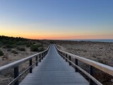 Fototapeta Na sufit - Boardwalk to the ocean, orange horizon, blue pure sky, no people