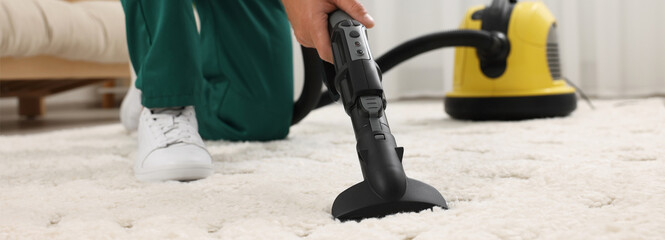 Poster - Dry cleaner's employee hoovering carpet with vacuum cleaner in room, closeup. Banner design