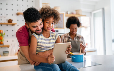 Wall Mural - Happy african family having fun with device at home. Black parents and child using digital tablet