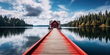 A Wooden Dock Leading To A Red Building On A Lake.