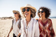 © Jasmina - Portrait of three middle aged female friends walking on the sea shore laughing. Diverse mature women strolling along a beach on vacation