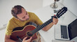 © astrosystem - Man playing acoustic guitar at home.