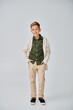 © LIGHTFIELD STUDIOS - vertical shot of preteen little boy in casual outfit on gray backdrop with hands in pockets, fashion