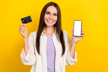 Poster - Photo of intelligent nice woman dressed white jacket demonstrate smartphone screen hold debit card isolated on yellow color background