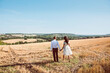 © fStop - Couple Walking in a Field Holding Hands