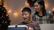 © PR Image Factory - asian woman standing behind her husband and releasing hands from his eyes while giving surprise gift for Christmas celebration. man kissing his wife with joy