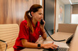 A girl administrator of a medical center sits at the reception and makes appointment for patients to see doctor by phone