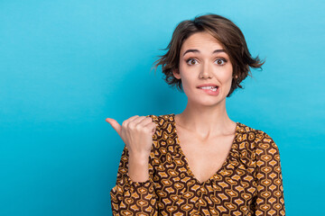 Canvas Print - Photo of pretty nervous person biting lips indicate thumb finger empty space isolated on blue color background