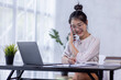 © David - Cheerful Young business Asian woman freelancer making telephone call share good news about project working in office workplace, business finance concept.