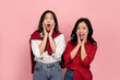 © PBXStudio - Two tanned Asian female friends are looking surprised at a promotion on a pink background. Beautiful girl acts shocked