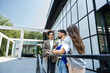 © Srdjan - Three business people waiting in front of office building taking a break, before staff meeting. Lawyers and law students on practice outside the court. Professional occupation concept