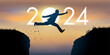 Un homme saute par dessus un gouffre entre deux falaises devant un soleil au zénith et symbolise le passage à la nouvelle année 2024.