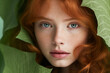 Beautiful girl with red hair freckles in the face looking from green leaves. Banner for beauty skin body care bio eco cosmetics concept