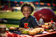 Niño pequeño de raza negra disfrutando de una barbacoa en el día de partido de futbol. 