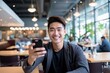 © vasyan_23 - happy asian man takes a selfie on a smartphone against the background of a cafe
