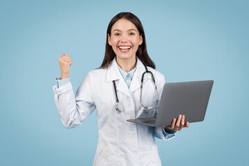 Wall Mural - Excited doctor with laptop making fist pump