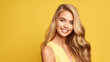© Uwe - Beautiful elegant european blond-haired smiling young woman with perfect skin and long blond hair, on a yellow background, close-up