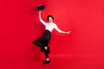 Sticker - Full body photo of cheerful positive young woman raise tray dance hostess isolated on red color background