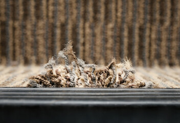 Frayed carpet coming loose on stairstep, stair nosing or stair edging. Close up of high traffic staircase with commercial carpet damage by the edge, causing tripping hazard. Selective focus.