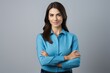 © Adriana - Happy young smiling confident professional business woman wearing blue shirt, pretty stylish female executive looking at camera, standing arms crossed isolated at gray background