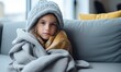 © Eli Berr - Toddler girl wear hat wrapped in plaid sit alone shivering from cold on sofa, heated apartment without heating due debt. Unhealthy child feeling discomfort try to warming up