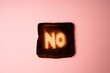 burnt slice of white bread toast with the word No on it on pink  background passionate ardent disagreement. poster creative rejection concept composition 