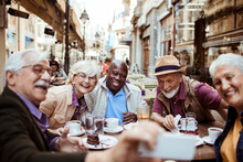 Group Of Senior Tourists Capturing A Selfie While Enjoying Desserts In A City Cafe