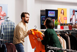Angry mad man and woman shoppers arguing in clothing store. Aggressive diverse people customers fighting over last clothing item at discounted price while shopping during Black Friday sales