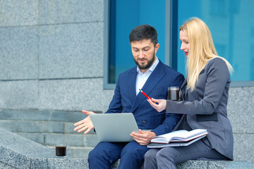 Wall Mural - Communication of business partners in an urban setting. successful businessmen man and woman with documents and laptop in hands discuss business projects. Business and trust at work