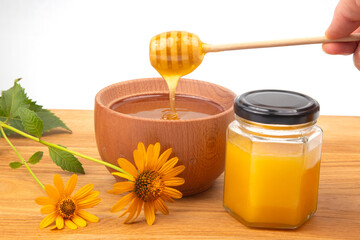 fresh floral honey dripping from a spoon into a wooden plate on a white background. organic vitamin health food