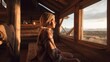Beautiful girl lookin out of window from wooden cabin at golden hour, sunset 