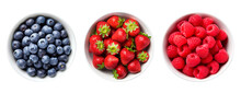 Top view of blueberries, strawberries and raspberries in bowls over isolated transparent background