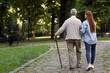 © New Africa - Senior man with walking cane and young woman in park, back view. Space for text