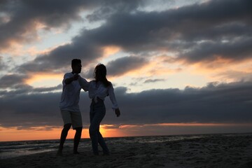 Wall Mural - Happy couple dancing on beach at sunset