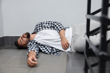 Wall Mural - Unconscious man lying on floor after falling down stairs indoors