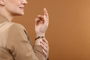 Sticker - Woman with elegant bracelets on brown background, closeup. Space for text