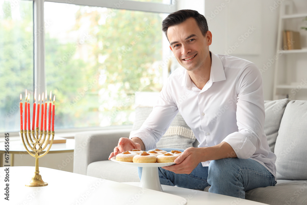 Young man with donuts celebrating Hanukkah at home