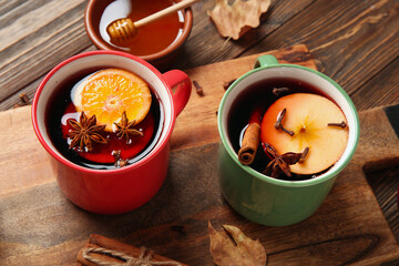 Wall Mural - Cups of hot mulled wine with apple and orange on wooden background