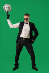 Wall Mural - Cool mature man in suit with disco ball on green background