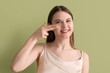 © Pixel-Shot - Young woman with acne problem applying cream on green background, closeup