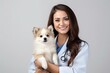handsome woman veterinarian doctor with stethoscope holding cute dog in arms in veterinary clinic on white background