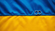 © WellStock - Wedding rings lie on the flag of Ukraine. Panoramic view