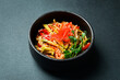 Udon pasta with vegetables and ginger. In a black plate. Japanese cuisine. On a dark background, close-up.