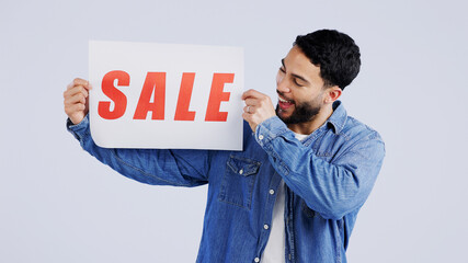 Canvas Print - Man, sale and excited with board in studio mockup, shopping discount and advertising retail announcement. Young person, arab and marketing for deal promotion with product launch by white background