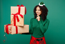 Minded Merry Little Kid Teen Girl Wear Hat Casual Clothes Posing Hold Stack Of Present Boxes With Gift Ribbon Bow Isolated On Plain Green Background Studio. Happy New Year Christmas Holiday Concept.